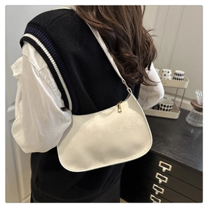 Detailed view of white embossed leather underarm bag worn by model in a chic indoor setting