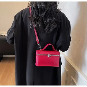 Détail d'un sac à bandoulière en cuir rouge vif avec texture grainée et zip métallique