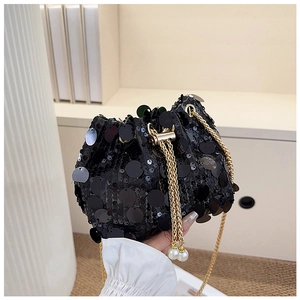 Detail of black sequined bucket bag featuring a gold chain and elegant pearl drawstring