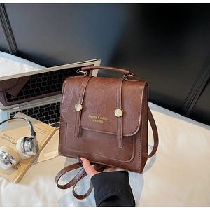 Detail of vintage brown leather backpack with golden metal buckle on a desk
