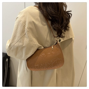 Detail of brown faux snake skin texture on minimalist crescent-shaped shoulder bag