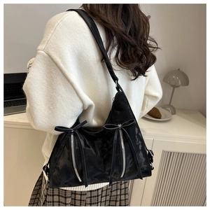Detail view of black tote bag featuring double bow ribbons and silver zippers on desk