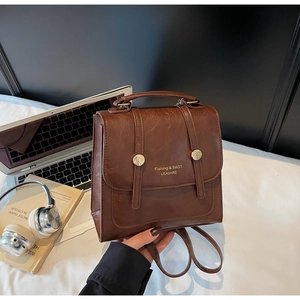 Detail of vintage brown leather backpack featuring a top handle and metallic rivets