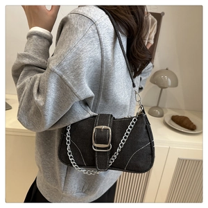 Detail of vintage black denim shoulder bag with white stitching and silver metal buckle