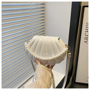Detail of snake-embossed leather texture and pearl handle on shell-shaped white bag