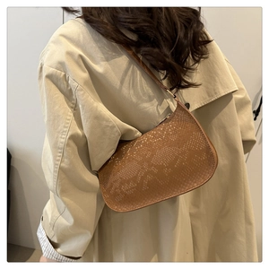 Detail of brown faux leather shoulder bag with snakeskin embossing and curved silhouette