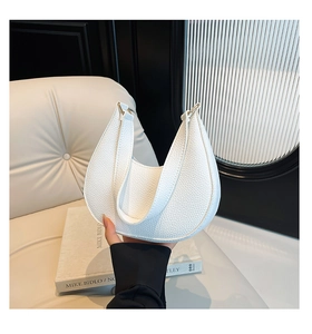 Detail of white half-moon shoulder bag in pebble grain leather with gold buckle detail