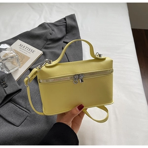 Vue macro du mini sac boîte jaune citron en cuir grainé avec fermetures éclair argentées