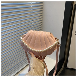 Close-up of pink shell-shaped bag with pearl chain strap and radial texture detail