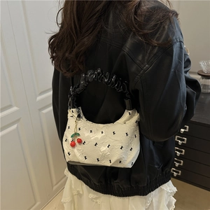 Minimalist white textured crescent crossbody bag with black handles and cherry charm detail