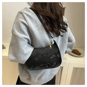Detail of black mesh underarm bag with gold zipper shown in a lifestyle setting