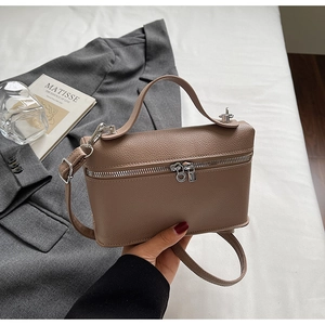 Détail du sac vanity en cuir grainé marron avec ferrures argentées et poignée haut