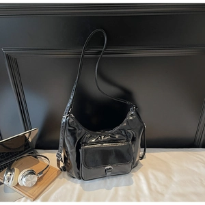 Détail du sac hobo en cuir verni noir avec poche avant à rabat et bandoulière réglable
