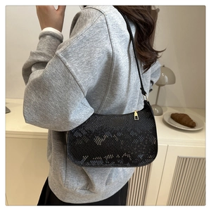 Close-up of black faux snake skin texture and gold metal hardware on the underarm bag