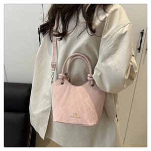Detail showing pink faux leather bucket bag texture and gold brand logo on the side