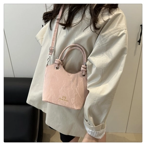 Close-up of pink bucket bag with marble texture and golden branding on the front