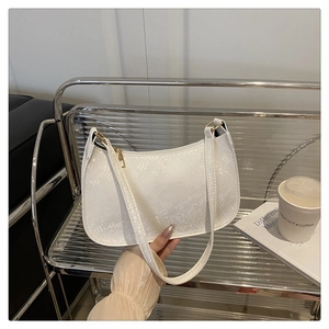 Close-up of white embossed snake texture on a stylish women's hobo shoulder bag with gold hardware