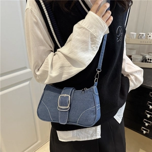 Retro denim crossbody bag with silver buckle and white stitching in casual home setting