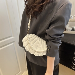 Elegant pearl white shell crossbody bag with pearl handle and quilted texture on model