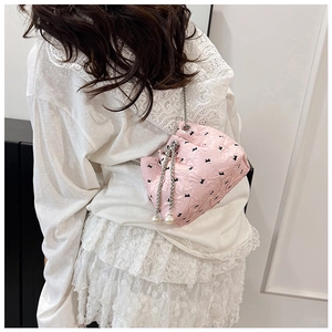 Detailed view of pink drawstring bucket bag with black bows and pearl pendants on model