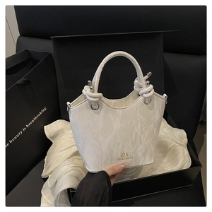Detailed view of white marble pattern bucket bag with braided rope handles and gold logo