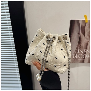 Detailed view of bucket bag with butterfly embroidery and pearl drawstring charms