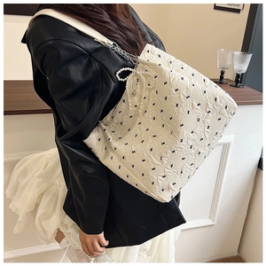 Photo de style d'un sac cabas blanc matelassé avec motifs lapins et breloque perle