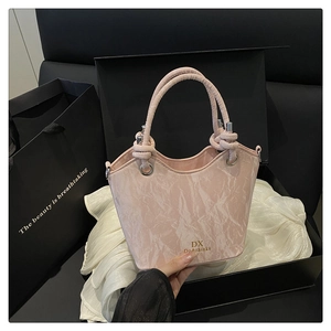 Detail of light pink marble pattern bucket bag with knot handle and golden brand logo