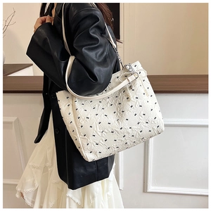Cabas matelassé blanc avec broderie nœuds noirs et chaîne en perles sur mannequin