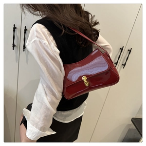 Close-up of red patent leather baguette bag with golden metal buckle and glossy finish
