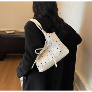 Détail du sac à bandoulière blanc texturé avec motifs lapins noirs et nœud latéral