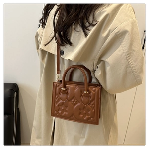 Detail of caramel embossed flower pattern on women's luxury faux leather handbag
