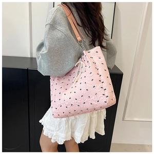 Détail d'un sac cabas rose avec motifs de nœuds et pendentif en perles