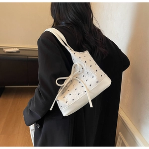 Détail d'un sac à bandoulière blanc matelassé avec grand nœud et broderies noires