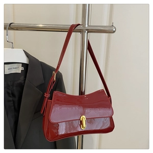 Detail of red glossy patent leather baguette bag with premium golden hardware clasp