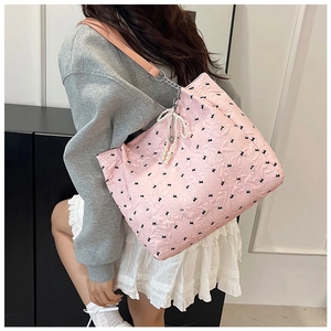 Détail du sac cabas matelassé rose avec nœuds noirs et pendentif en perles