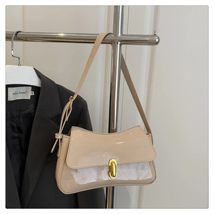 Detail of glossy beige patent leather baguette bag with a golden oval metal buckle clasp