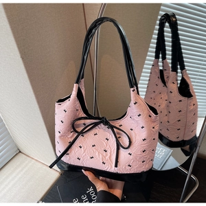 Vue détaillée du sac à bandoulière matelassé rose avec nœuds noirs et cuir verni