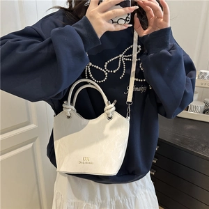 Chic white embossed bucket bag with gold logo shown as a stylish crossbody on a model