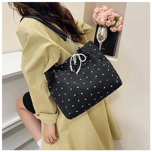 Détail du sac cabas noir texturé avec motifs papillons blancs et breloque en perles