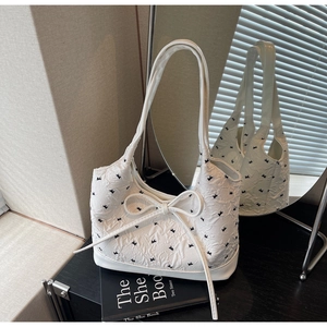 Détail du tissu à motif nœud texturé et du grand ruban sur le sac à bandoulière blanc