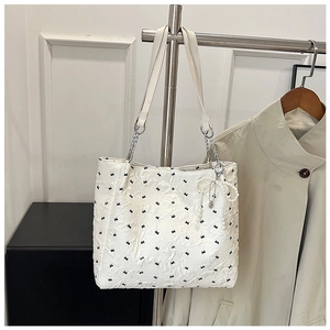Détail du sac cabas matelassé blanc avec broderie nœud noir et breloque en perles élégante