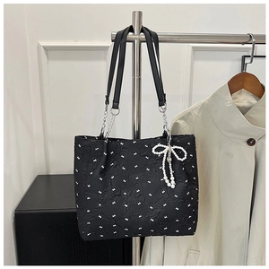 Détail du sac cabas plissé noir avec motifs nœuds et breloque papillon perlé
