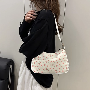 Chic white underarm bag with red cherry print featuring a crescent shape and slim strap