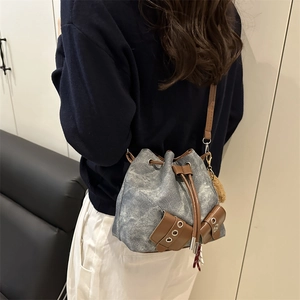 Vintage denim bucket bag with brown leather drawstring and plush ball charm in retro style