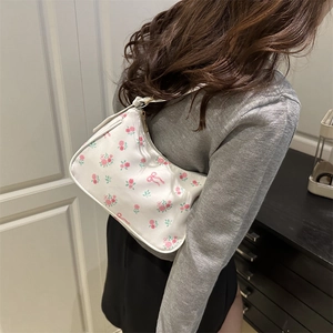 Floral crescent shoulder bag with pink roses and bow patterns shown on a female model