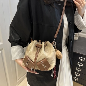 Retro canvas bucket bag with brown leather trim and pompom charm in home interior