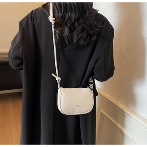 Back view of model wearing white lychee grain leather crossbody bag with knot strap