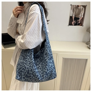 Blue leopard print tote bag with wide shoulder straps in a minimalist indoor setting
