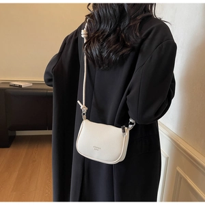 Detail of off-white lychee texture leather crossbody bag with knot design strap